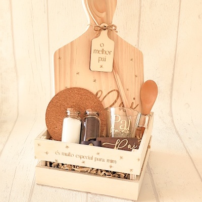 Conjunto de presente para pai com caixa de madeira, tábua de cortar, colher, garrafas com temperos, copo de vidro e texto personalizado.