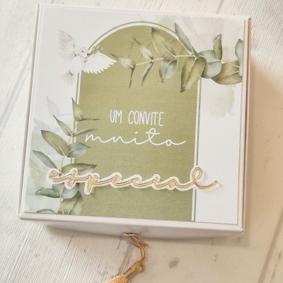 Caixa branca decorada com convite especial, folhas verdes e pomba