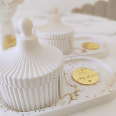 Caixas decorativas brancas em cerâmica com tampa canelada sobre bandeja branca com etiqueta dourada