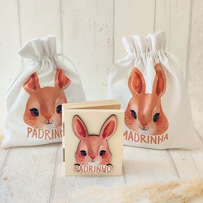 Sacos de pano e bloco de notas com imagem de coelho e texto padrinho/madrinha
