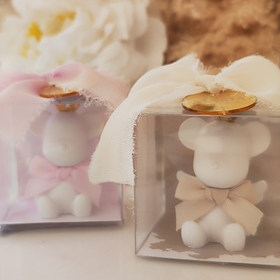 Ursinhos de cerâmica em caixas transparentes com laços de tecido rosa e bege e selo dourado