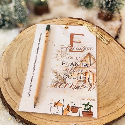 Cartão decorativo com lápis sobre tronco de madeira e árvores de Natal ao fundo