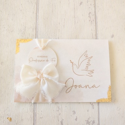 Cartão branco com bordas douradas, texto, desenho de pomba e laço de tecido branco