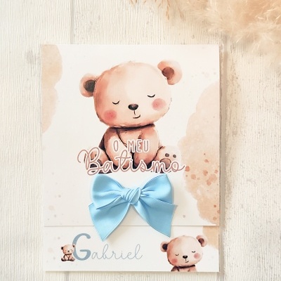 Cartão de batismo com ursinhos e laço azul sobre madeira clara