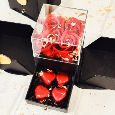 Caixa preta com rosas vermelhas artificiais e bombons vermelhos em forma de coração