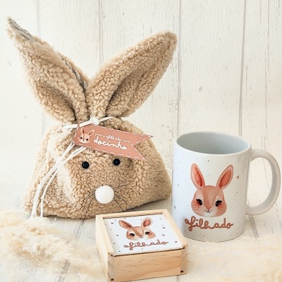 Saco peluche coelho, caneca branca com coelho desenhado e caixa de madeira com tampa com desenho de coelho.