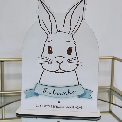 Objeto decorativo em forma de coelho com texto 'Padrinho' e 'ÉS MUITO ESPECIAL PARA MIM!' sobre superfície de vidro