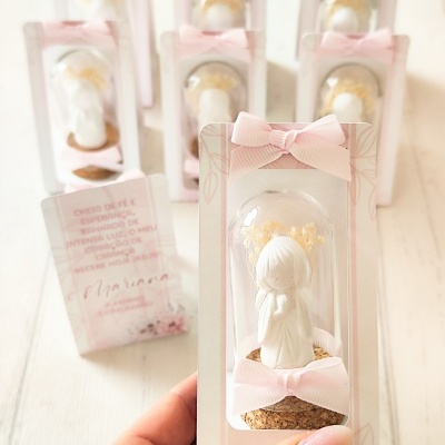 Miniatura decorativa de anjo branco dentro dunha cápsula de vidro con flores secas amarelas e lazos rosas