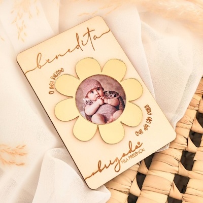 Placa de madeira com flor e foto de bebé, texto gravado em português.