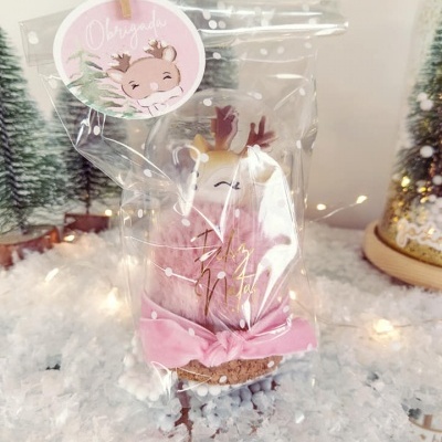 Pinheiro decorativo rosa com chifres dourados em embalagem plástica com etiqueta 'Obrigado' em fundo de neve artificial e árvores de Natal.