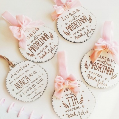 Ornamentos redondos em madeira com laços cor de rosa e textos em português para madrinhas e tias