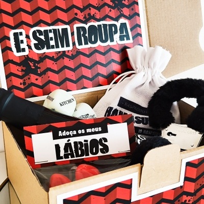 Caixa de cartão com objetos diversos e etiquetas com texto em padrão geométrico vermelho e preto