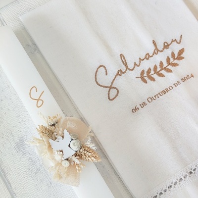 Toalha branca com bordado castanho e vela branca decorada com flores secas e laço bege