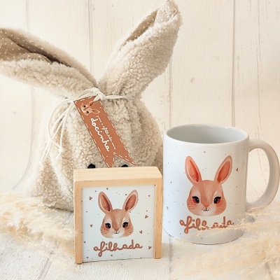 Conjunto com caneca, quadro e bolsa de pelúcia com imagem e texto de coelho e palavra 'afilhada'.