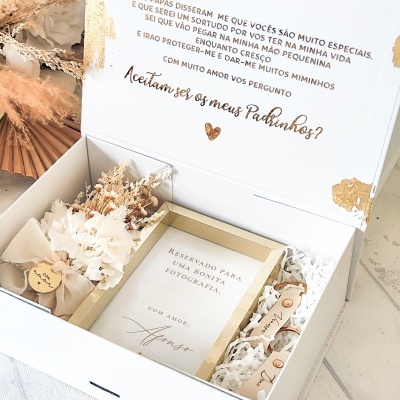 Caixa decorativa branca com moldura dourada, raminhos secos e etiqueta preta com texto em dourado