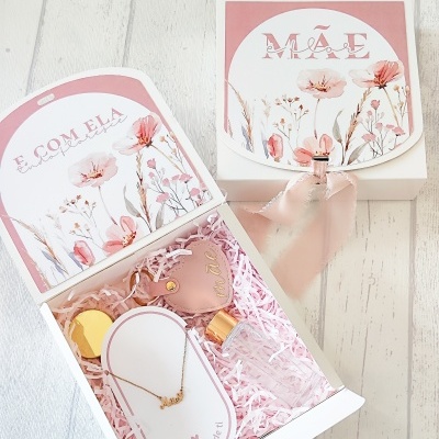 Caixa de presente branca com decoração floral e itens de joalharia e perfume.