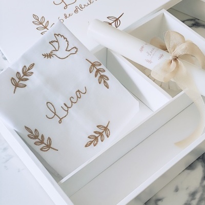 Conjunto de batismo com tecido branco bordado, caixa branca decorada e rolo de papel com fita bege