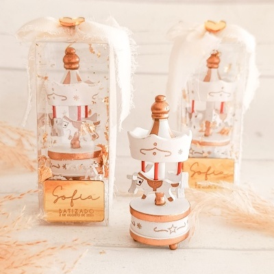 Figuras de carrossel decorativas em madeira com cavalos, laços brancos e etiquetas douradas em caixas transparentes.