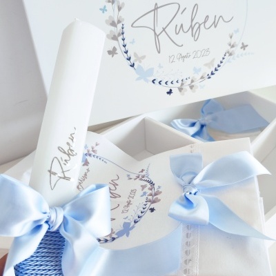 Conjunto de batismo com vela e toalha brancas e fitas azuis num estojo branco decorado