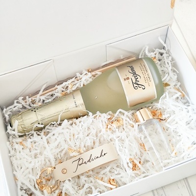 Caixa branca com garrafa de Freixenet, garrafa pequena e chaveiro com 'Padrinho'
