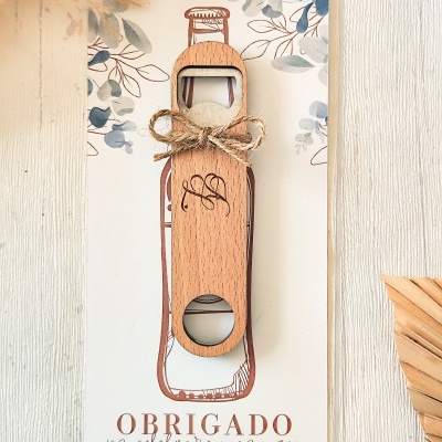 Abridor de garrafas de madeira com laço, colocado sobre cartão decorativo com texto de agradecimento