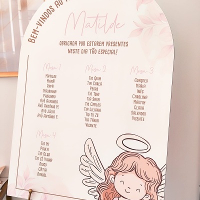 Placa branca arredondada para batizado com texto e lista de nomes, decorada com anjo desenhado, apoiada em cavalete de madeira