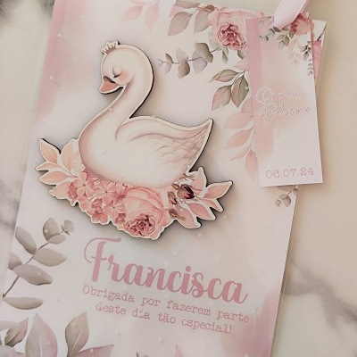 Cartão com cisne branco e flores, e pequeno cartão rosa com data e texto decorativo.