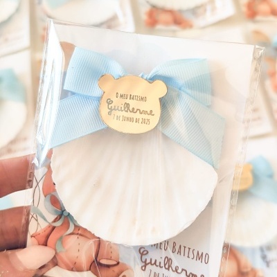 Concha decorativa branca com laço azul e placa de madeira com texto para batismo