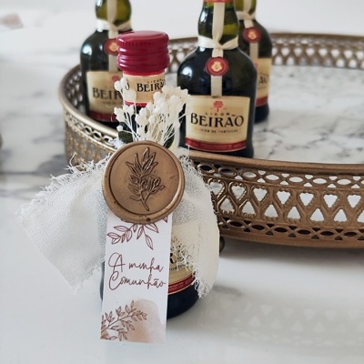 Mini garrafas de licor Beirão decoradas e colocadas numa bandeja dourada sobre mesa branca