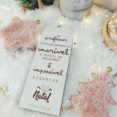 Etiqueta de Natal em madeira com texto e decoração natalícia sobre neve artificial