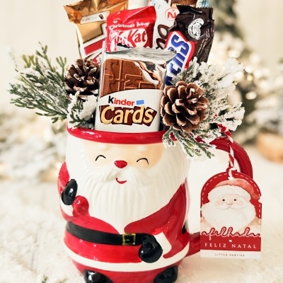 Caneca em forma de Pai Natal cheia de chocolates e decorada com pinhas e raminhos de pinheiro nevados
