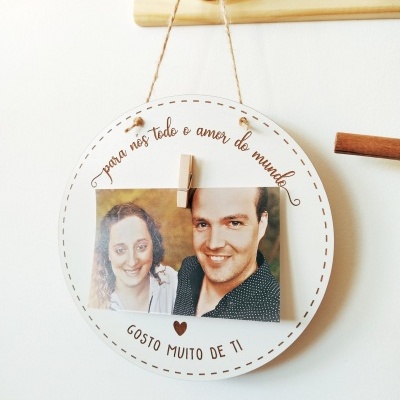 Placa decorativa redonda com fotografia e texto em português pendurada na parede