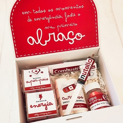 Caixa branca aberta com produtos de cuidados pessoais e caneta Nutella em fundo vermelho.
