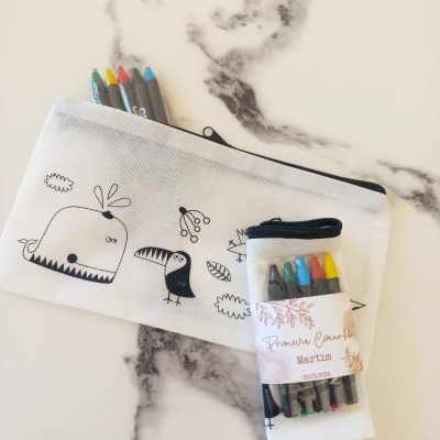 Estojo branco com ilustrações a preto e lápis de cor e embalagem com etiqueta de Primera Comunhão