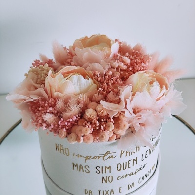 Arranjo floral artificial em caixa branca com texto dourado