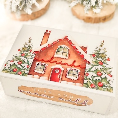 Caixa branca com desenho de casa de gengibre e árvores de Natal nevadas