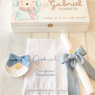Conjunto de batizado com caixa de madeira decorativa, toalha branca bordada, vela com fita azul e concha com laço azul