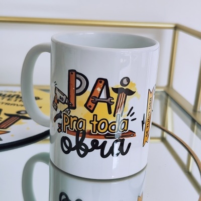 Caneca branca com texto colorido e asa sobre superfície espelhada