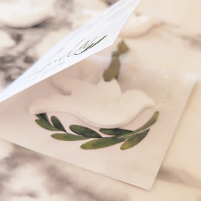 Cartão branco com relevo de pomba sobre ramo de folhas verdes