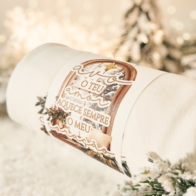 Manta creme com etiqueta de janela e texto em português sobre um fundo de decoração natalícia desfoque