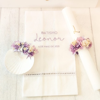 Conjunto de batismo com toalha bordada, vela decorada com flores e concha em fundo branco