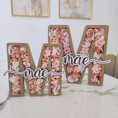 Duas letras decorativas M com flores artificiales rosa e bege e placa com 'mãe'