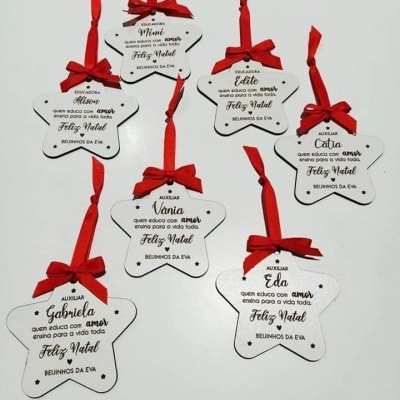 Etiquetas em madeira branca em forma de estrela com laços vermelhos e mensagens de Natal em português