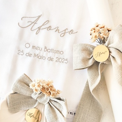 Toalha de batismo branca com bordados e velas decoradas com laços bege e flores secas