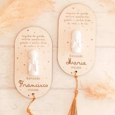 Dois quadros decorativos de madeira clara com anjos em relevo branco e franjas douradas