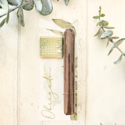Vela castanha embalada e cartão com texto Obrigado e calendário pequeno em superfície de madeira com folhas decorativas
