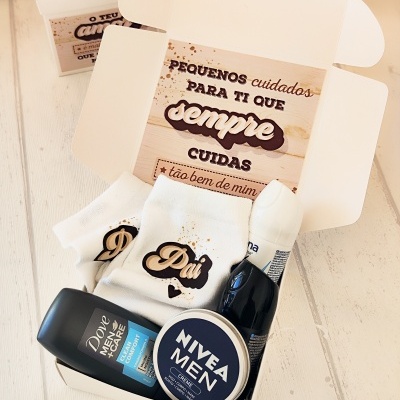 Caixa aberta com produtos masculinos para cuidados pessoais e camiseta com texto Pai