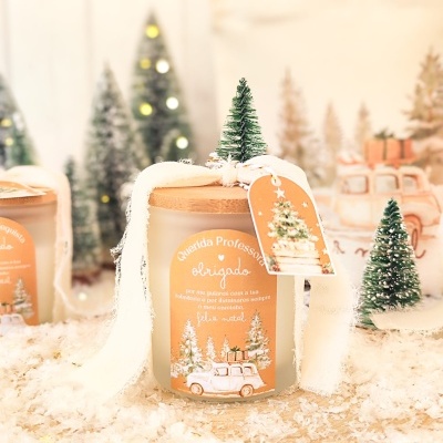 Vela decorativa natalícia com mini pinheiro e etiqueta laranja em jarro de vidro fosco.