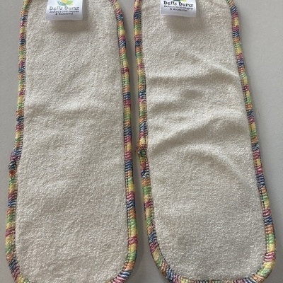 Dois absorventes reutilizáveis para fraldas com tecido branco e bordas coloridas