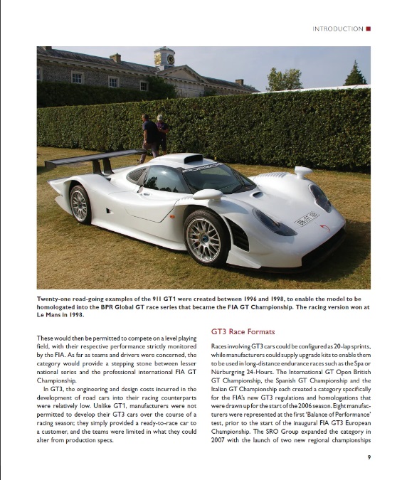 Porsche 911 GT3: Road and Track 1999-2024 Carro de corrida Porsche 911 GT1 branco estacionado num relvado junto a sebes e um edifício